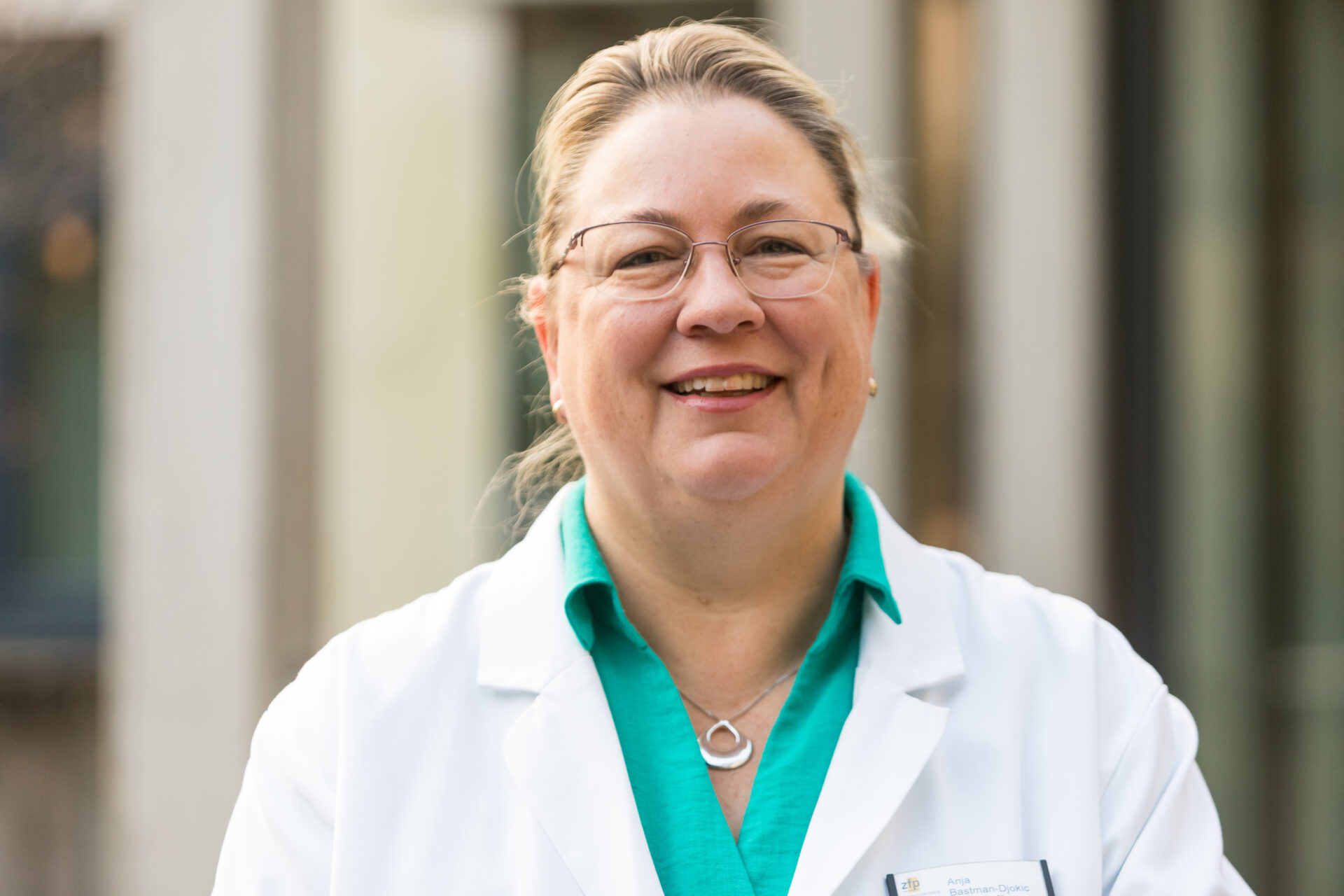 Porträt der lächelnden Ärztin Anja Bastman-Djokic in weißem Arztkittel.