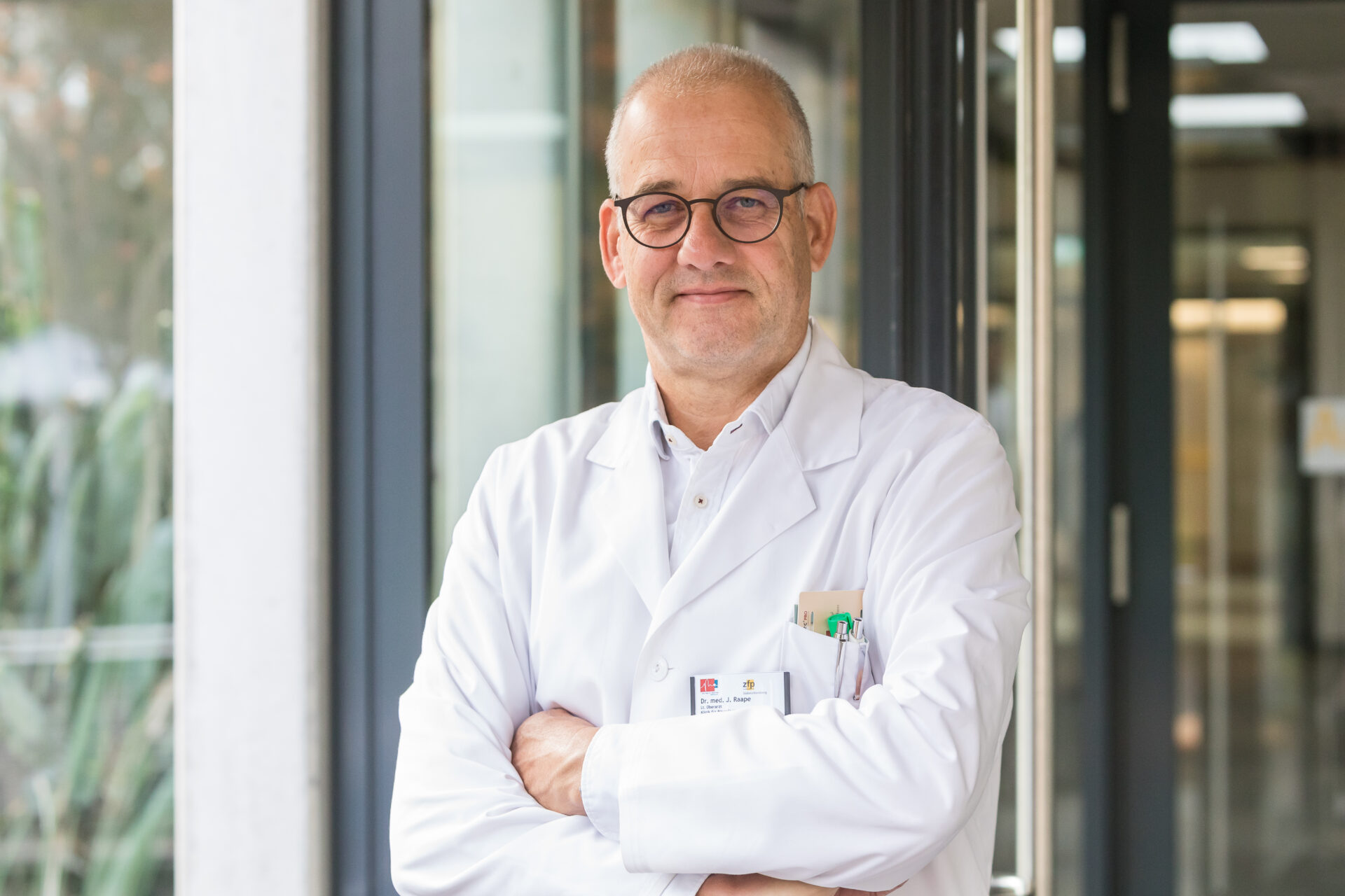 Porträt des lächelnden Arztes Jan Raape in weißem Arztkittel.