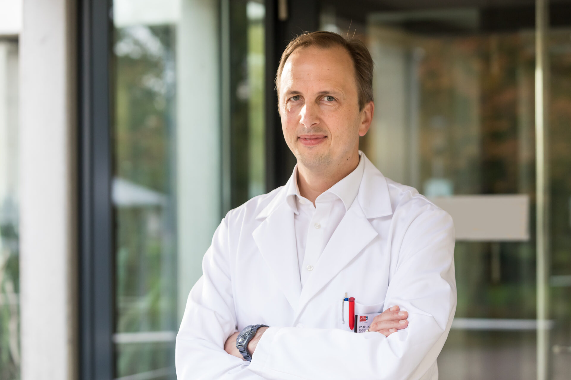 Porträt des lächelnden Chefarztes Christian Tilz in weißem Arztkittel.