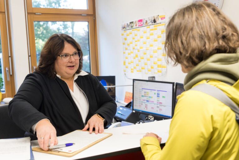 Mitarbeiterin aus dem Ambulanzsekretariat Frau Astrid Moosmann bespricht Anmeldeunterlagen mit einer Patientin.